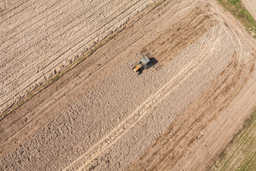Obraz premium aerial view of the tractor on harvest field