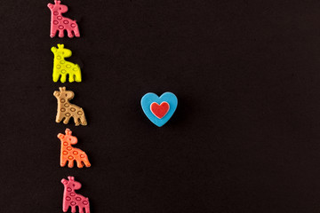 Multi-colored giraffes and heart on a black background