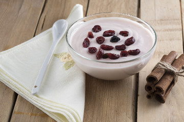 Closeup of delicious yogurt with red and black ribes on wooden table.High nutritional value