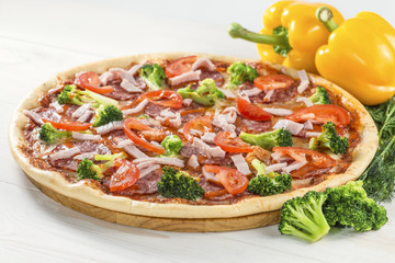 tasty pizza on a wooden board with pepper and broccoli