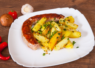 grilled meat sausages with fried potatoes in a plate on wooden table
