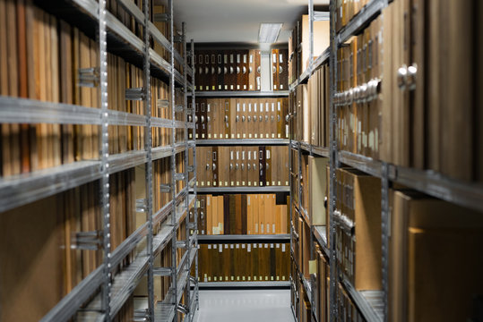 Indoor storage room details in a manufacturing enterprise, metal shelves with wooden brown office cases with folders.