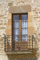 balcon con barandilla metalica  en edificio antiguo, con puertas y visillos