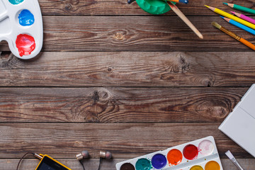 Paper, watercolors, paint brush and some art stuff on wooden   table