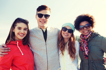 happy teenage friends in shades hugging outdoors