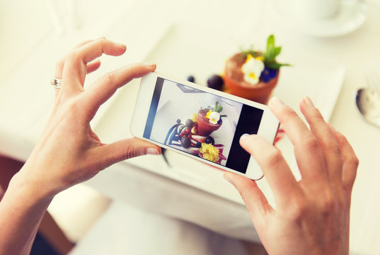 close up of woman picturing food by smartphone