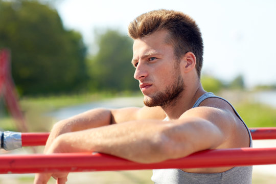 young man exercising on parallel bars outdoors