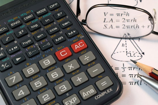 Eye Glasses, pen and pencil over the Formula with calculator