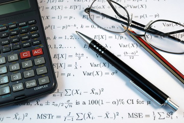 Eye Glasses, pen and pencil over the Formula with calculator
