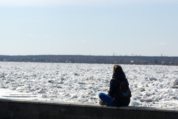 Fototapeta na wymiar A young woman watches the ice on the river
