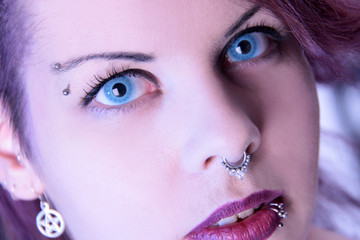 Gesicht einer Frau mit blauen Kontaktlinsen und Körperschmuck