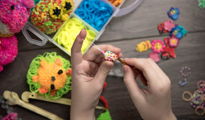 children's hands are weaving figures out colored rubbers