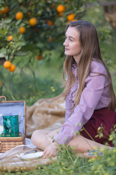 Young woman on picnic near orange tree
