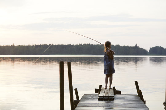 Rear view of girl fishing while standing on jetty