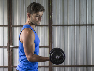 Young man lifting weights with his right arm during a workout at