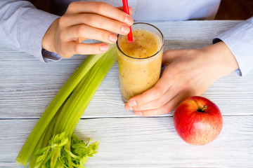 Woman drinking a smoothie of apples and celery, top view