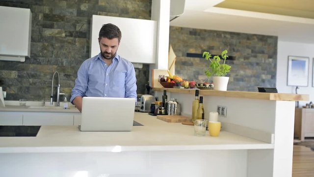 Man at kitchen countertop working on laptop from home