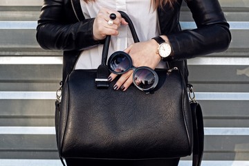 Fashionable woman with black handbag . Street style