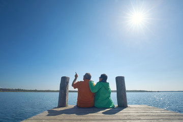 aktives Rentnerpaar sitzt in outdoor Kleidung am See