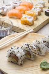 Different Sushi rolls,wasabi and ginger on a plate on wooden bac
