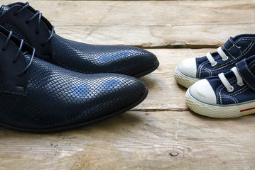 men shoes and kids sneakers standing facing each other, father's day