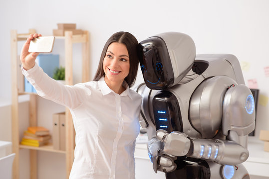 Positive girl making selfies with robot
