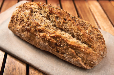 Loaf of homemade bread on wooden background, food closeup.