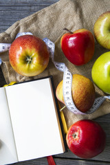 Apples with tape measure, Open notebook for notes. The concept of a healthy lifestyle and losing weight. Free space for text. Copy space. selective soft focus