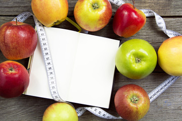 Apples with tape measure, Open notebook for notes. The concept of a healthy lifestyle and losing weight. Free space for text. Copy space. selective soft focus