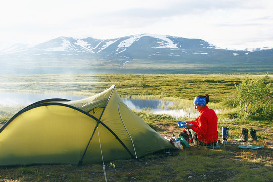 Woman camping by pond in mountains