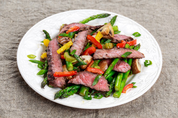 Grilled steak with stir-fried vegetables on plate.