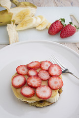 Stack of golden pancakes with strawberries, banana,
