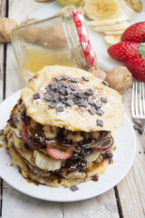 Pancakes with berries, fruits, chocolate, pine nuts and honey on