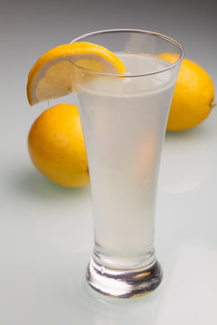 Glass of water and fresh lemon on a gray background
