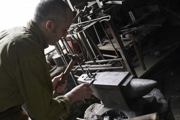 The blacksmith in the production of Handicrafts made of metal on the anvil in the workshop