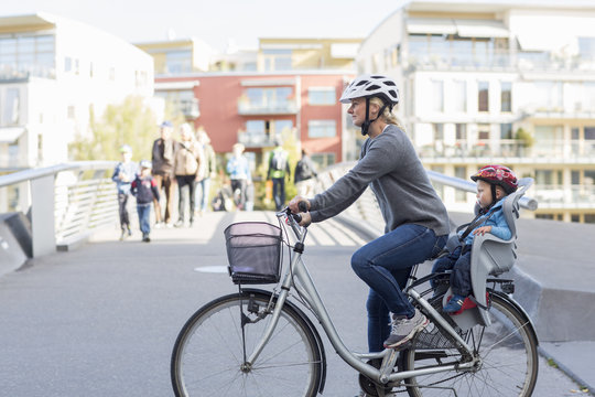 Woman riding bicycle with son sitting in back seat