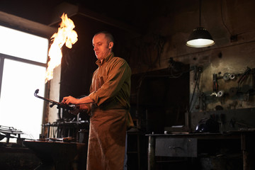 The blacksmith heats the gas burner before working in the workshop