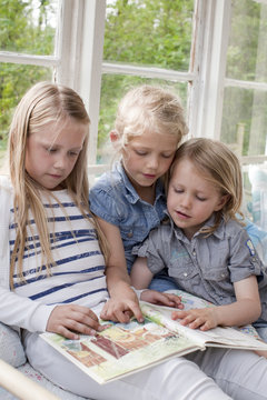 Three girls reading book