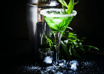 Green alcoholic cocktail with ice in a martini glass decorated w