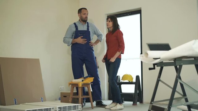 Woman and male worker talking to each other at new home
