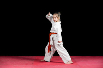 Little girl practice karate isolated on black
