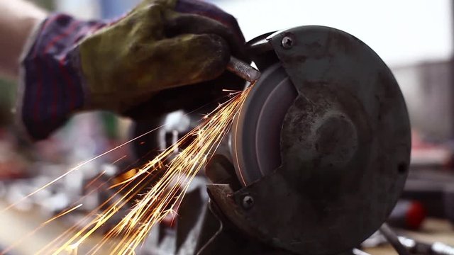 Color video of a worker polishing a piece of metal at a grinder.