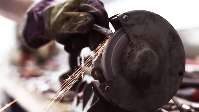 Color video of a worker polishing a piece of metal at a grinder.