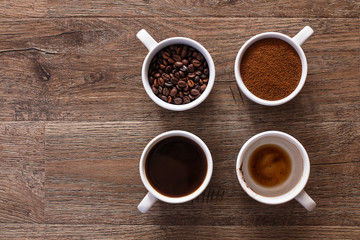 Four cups of coffee, phases of drink - bean, ground and empty cup.