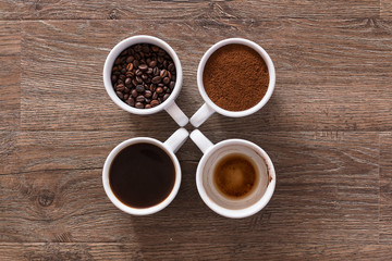 Four cups of coffee, phases of drink - bean, ground and empty cup.
