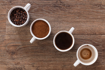 Four cups of coffee, phases of drink - bean, ground and empty cup.