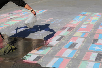 London, UNITED KINGDOM, 09.04.2016. A man cleaning states flags made of chalk, symbolizing nation states crisis