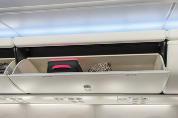 Carry-on luggage in overhead storage compartment on airplane.