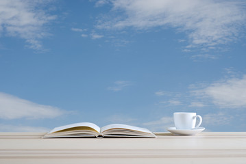 book and coffee cup on blue sky background
