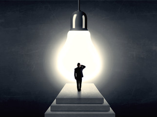 Man standing on a step in front of a huge light bulb